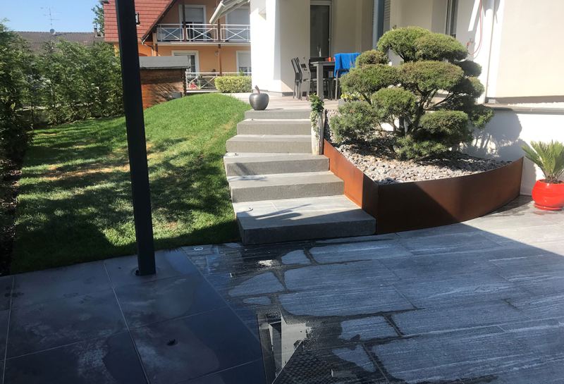 Escalier en pierre, bac en acier corten et arbre taillé en nuage