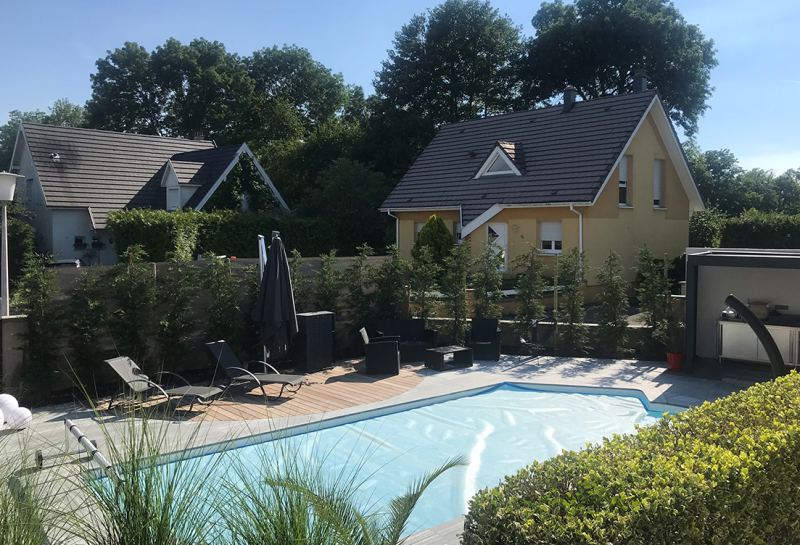 Piscine entourée de transats et de haies dans un jardin