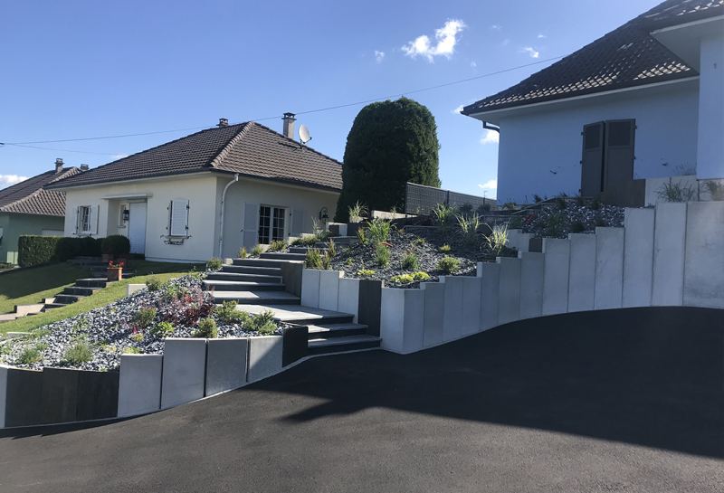 Jardin en terrasses avec jardinières en béton et plantations de graminées